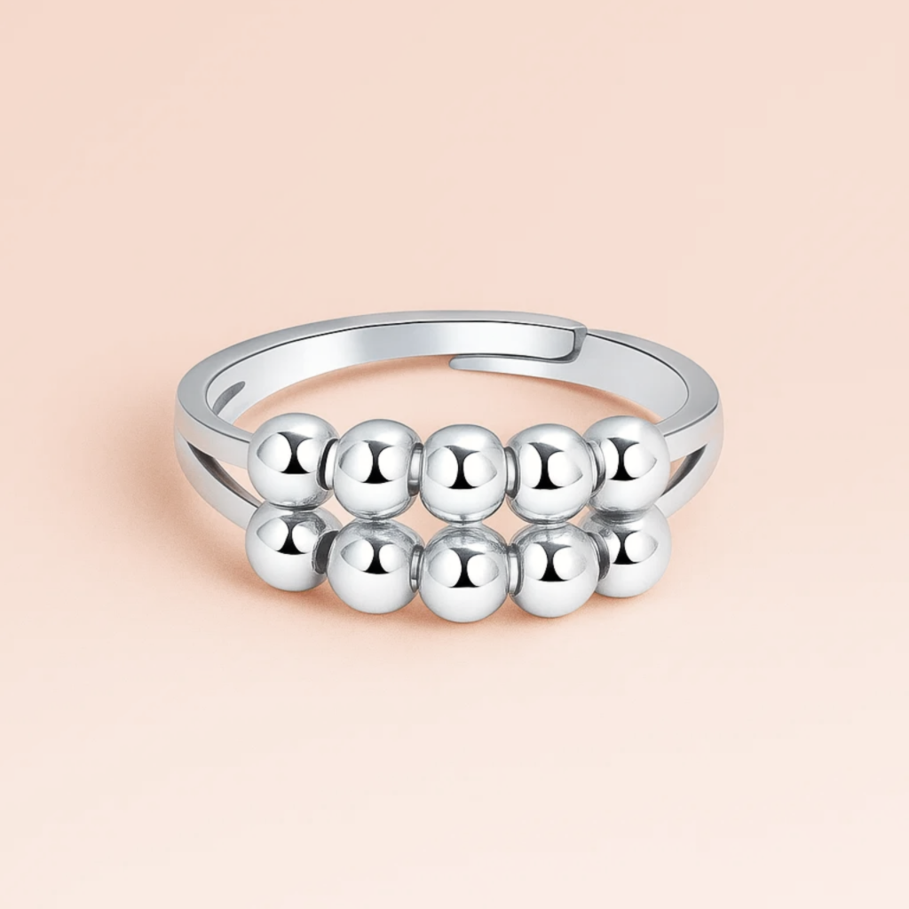 Silver ring with spherical beads on a beige background