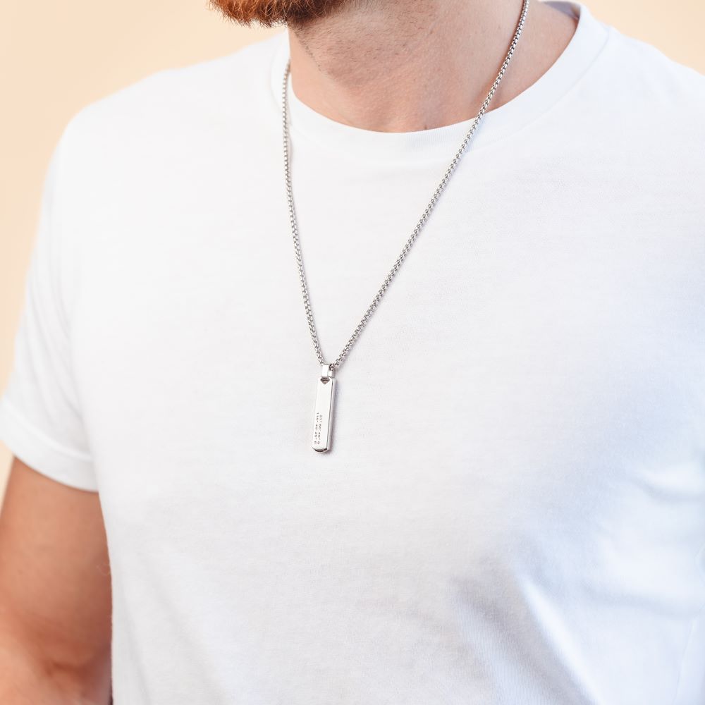 A man wearing a long silver pendant necklace 