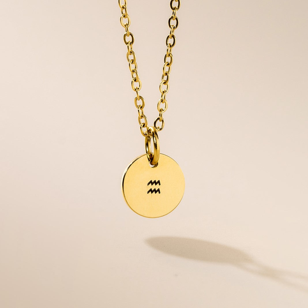 A gold necklace with Aquarius sign pendant