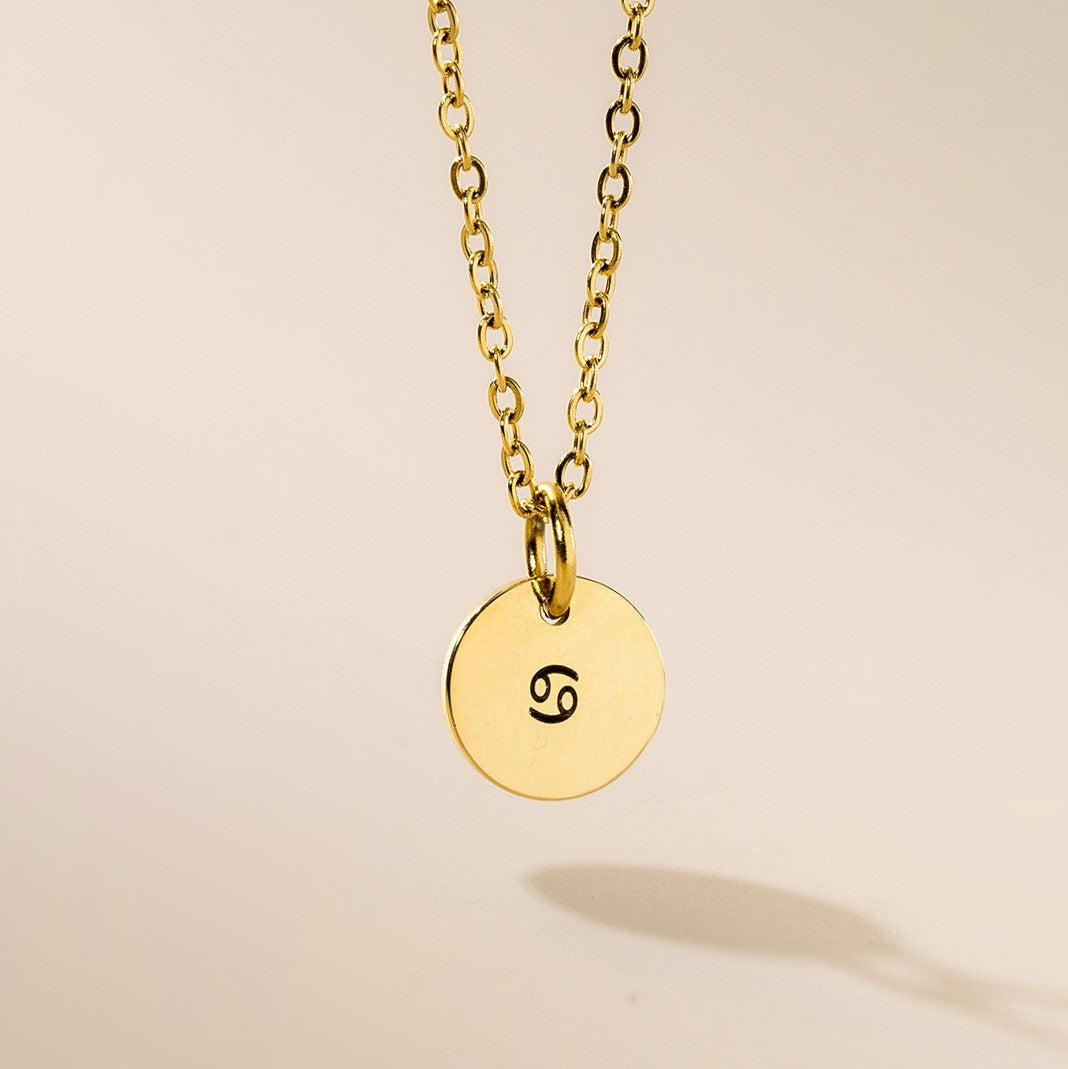 A gold-plated zodiac pendant necklace with a chain, featuring the engraved zodiac sign Cancer.