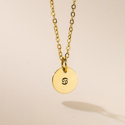 A gold-plated zodiac pendant necklace with a chain, featuring the engraved zodiac sign Cancer.