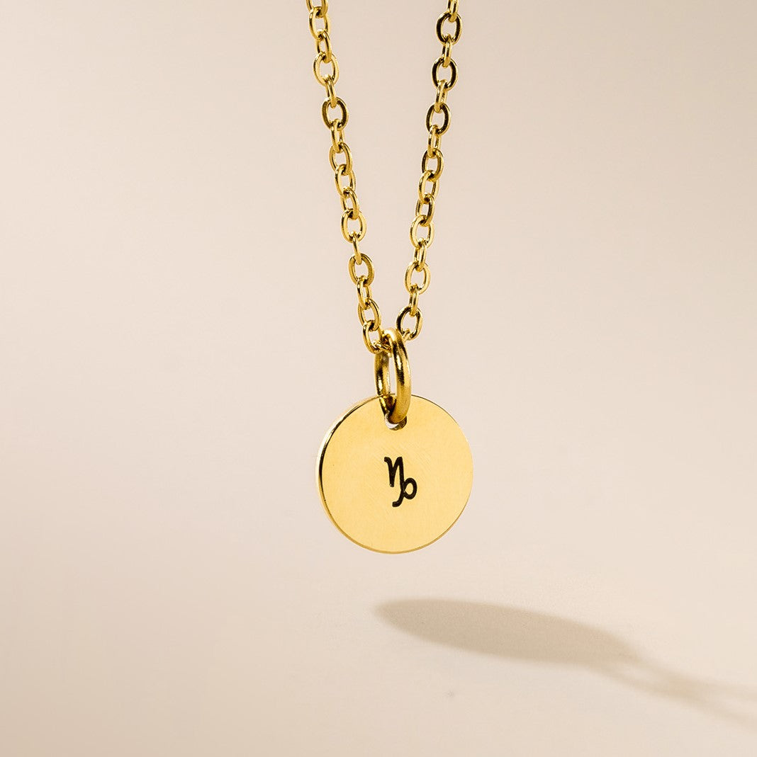 A gold-plated pendant necklace with a gold chain, featuring the zodiac sign Capricorn engraved on a 10mm diameter pendant.