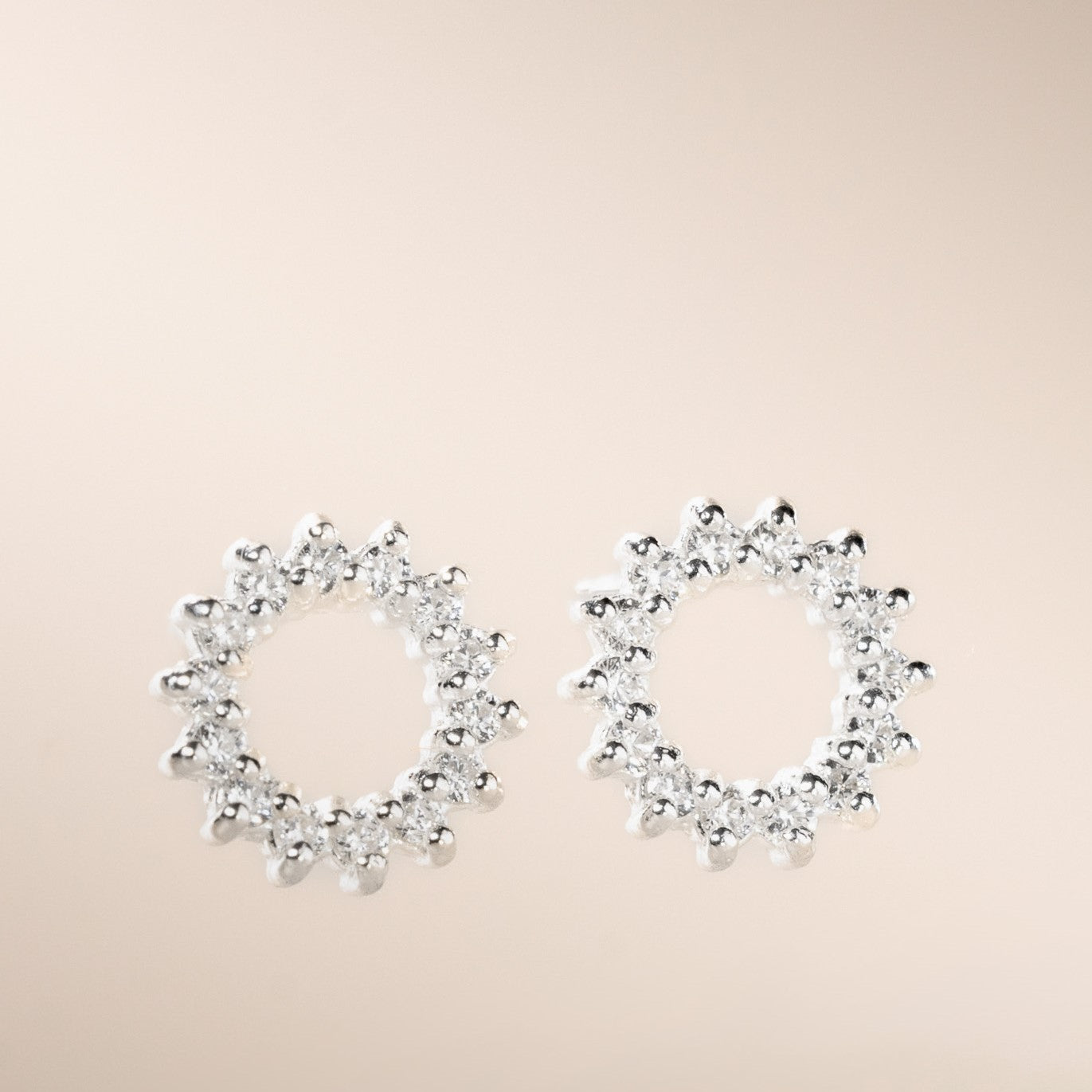 A pair of silver-colored open circle stud earrings with cubic zirconia stones