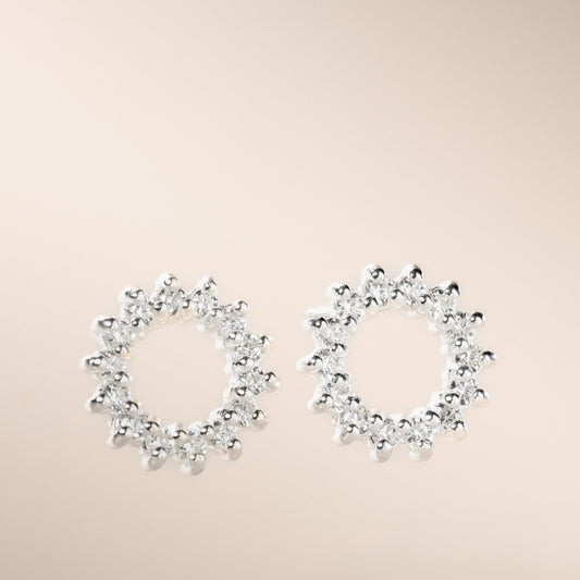 A pair of silver-colored open circle stud earrings with cubic zirconia stones