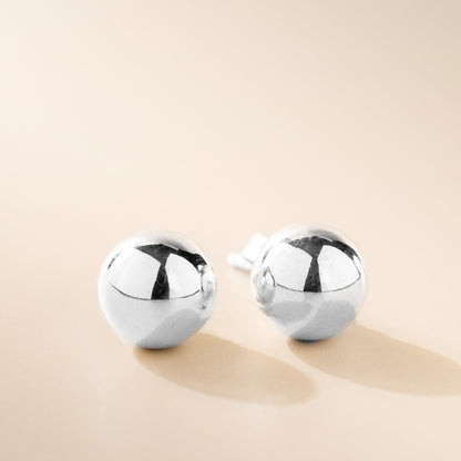 A pair of silver ball stud earrings on a light background.