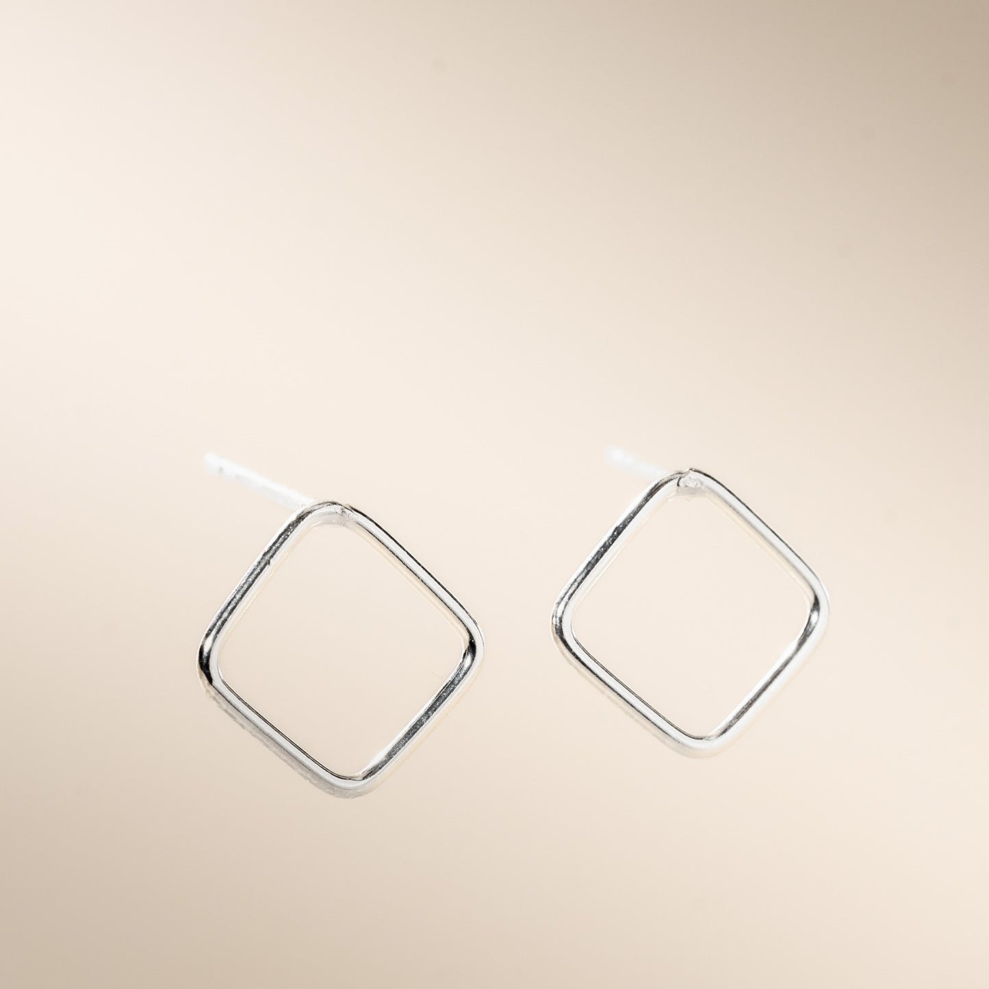 A pair of silver open square stud earrings displayed against a neutral background.