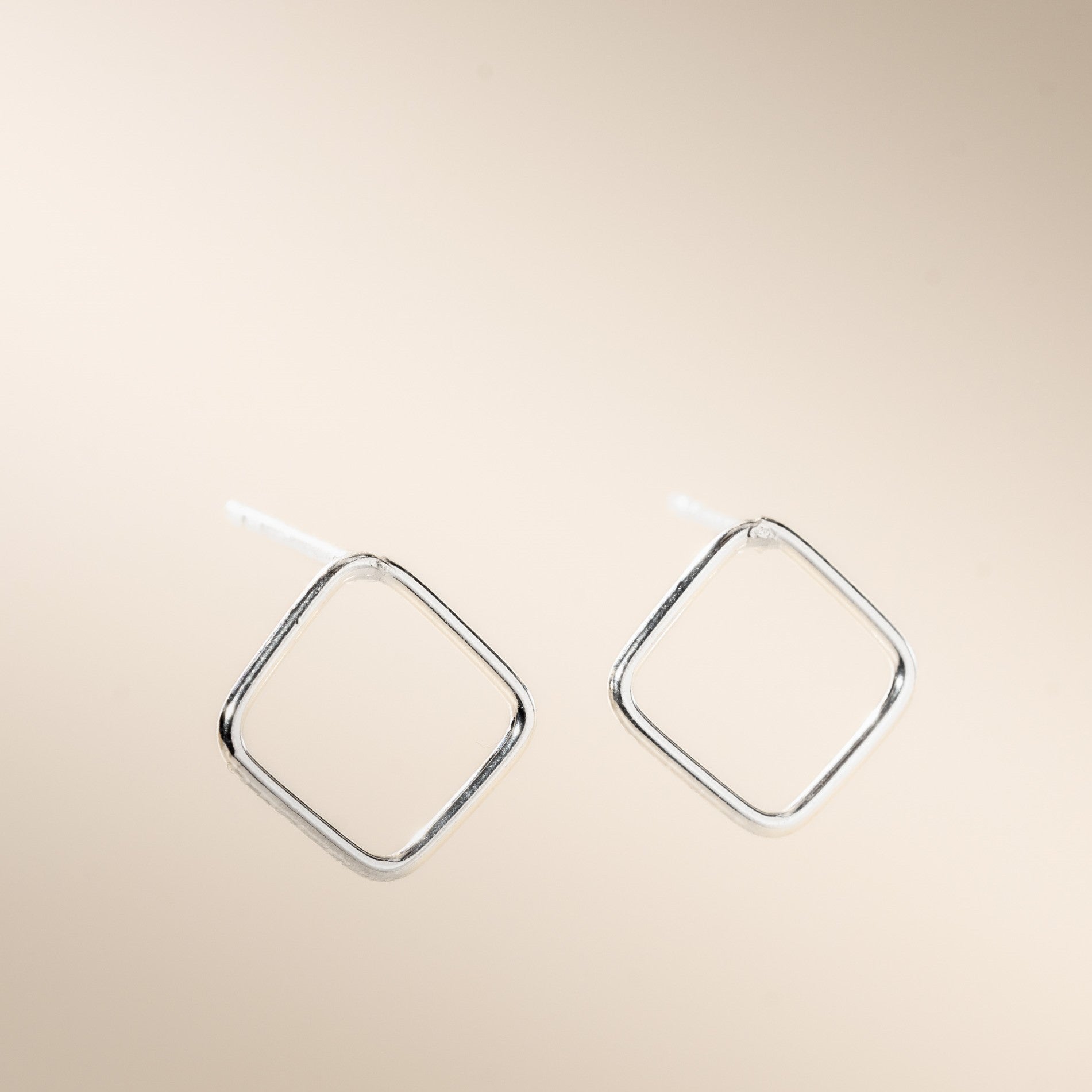 A pair of silver open square stud earrings displayed against a neutral background.