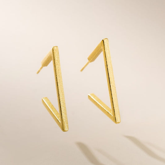This image features a pair of elegant Abstract Hoop Earrings. The earrings are designed with a minimalist aesthetic, showcasing a simple yet sophisticated golden hoop shape.