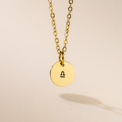 A gold necklace with Libra sign pendant