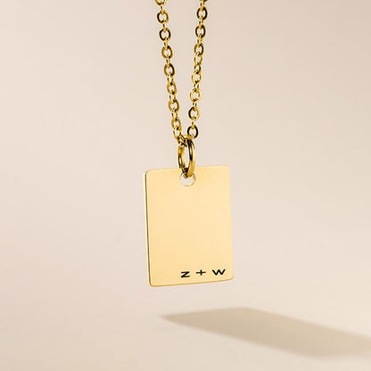 A gold-plated personalized necklace with a small rectangular tag pendant attached to a gold-plated chain.
