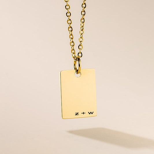 A gold-plated personalized necklace with a small rectangular tag pendant attached to a gold-plated chain.