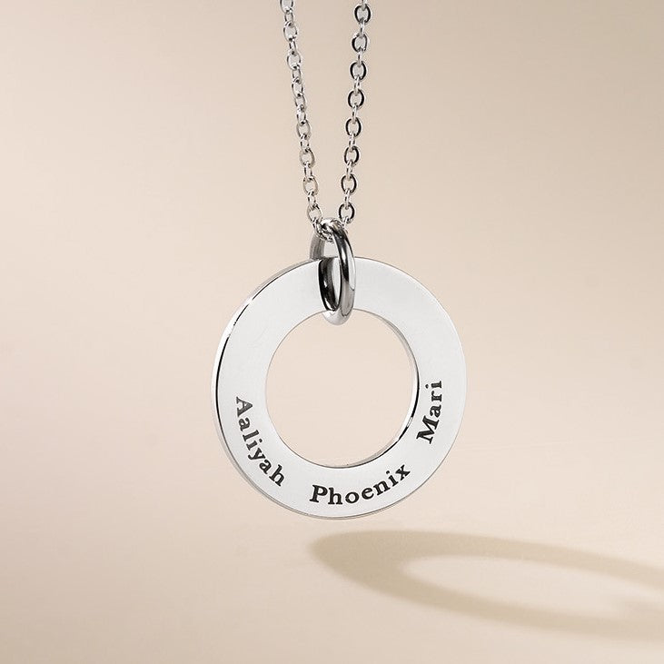A silver-colored necklace with a round pendant featuring the engraved text 'Aiyahh Phoenix' on a chain.