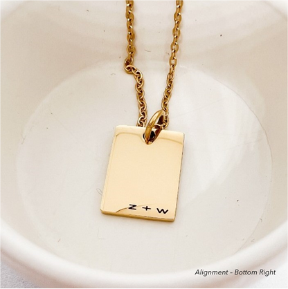 A gold rectangular pendant with letters engraved