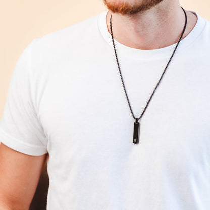 A man wearing a long black pendant necklace