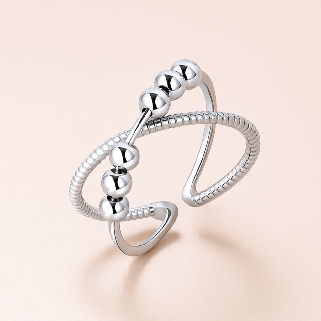 Silver ring with bead-like design on a beige background