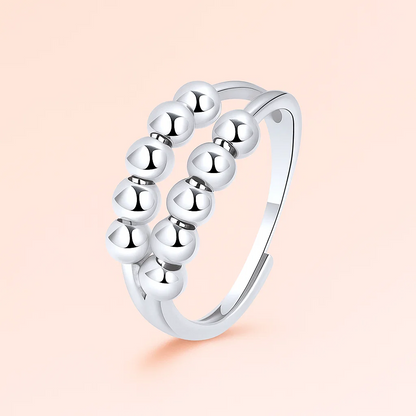 Silver ring with bead design on a light pink background