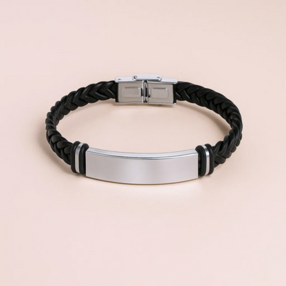 Black braided bracelet with a silver tag on a beige background