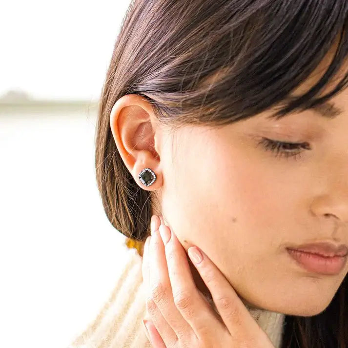 Close-up of a woman wearing a black stud earring on a blurred background
