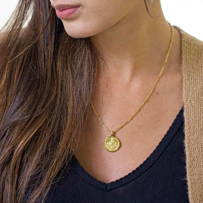 Woman wearing a gold necklace with a compass pendant