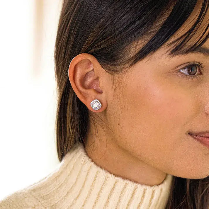 Close-up of a woman wearing diamond stud earrings with a blurred background