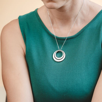 A woman wearing a large washer pendant necklace