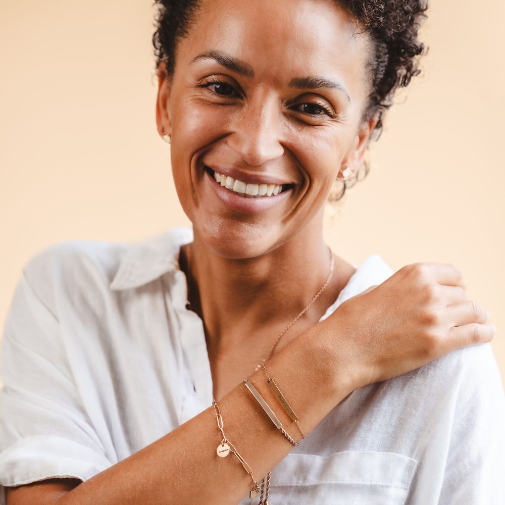 A woman wearing a stack of engraved bracelets in rose gold colour