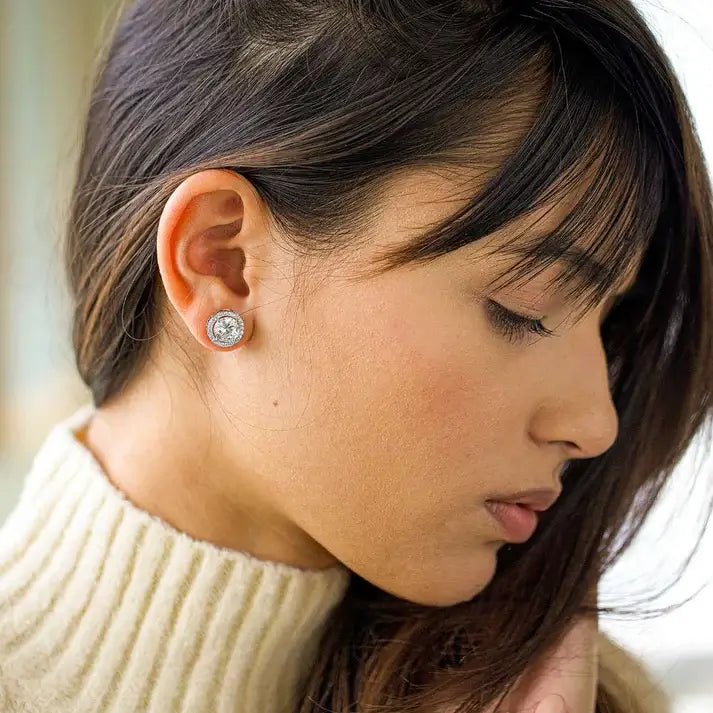 Close-up of a woman wearing diamond stud earrings with a blurred background