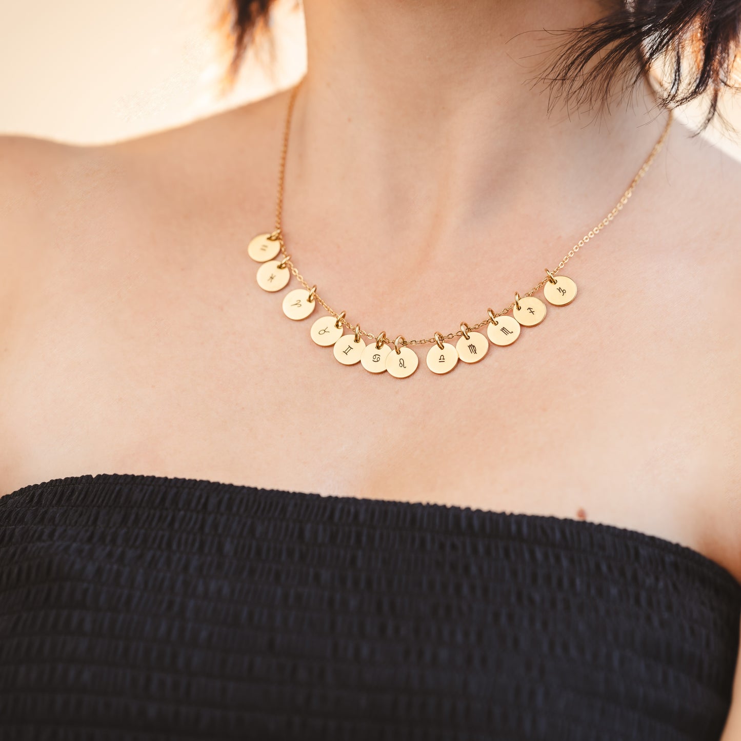A girl wearing a necklace with all horoscope pendants