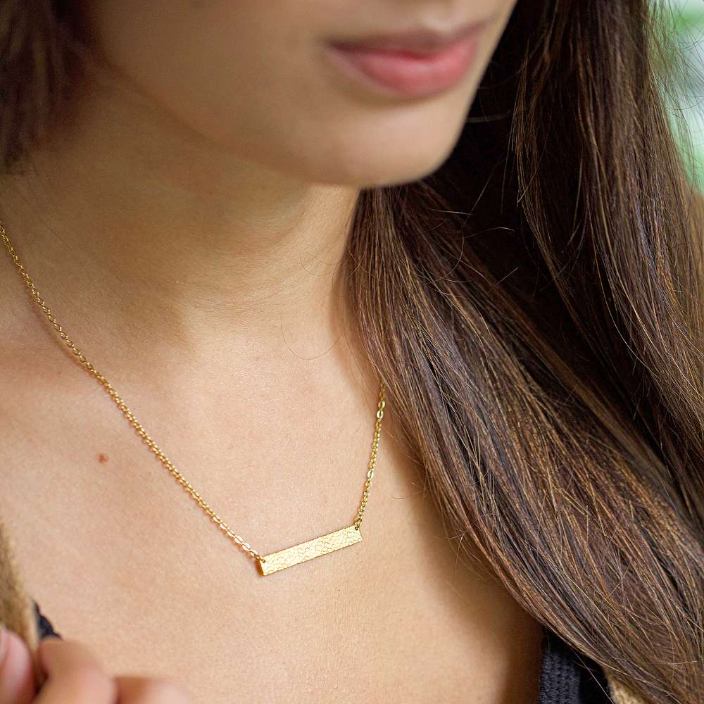 A girl wearing a hammered bar necklace